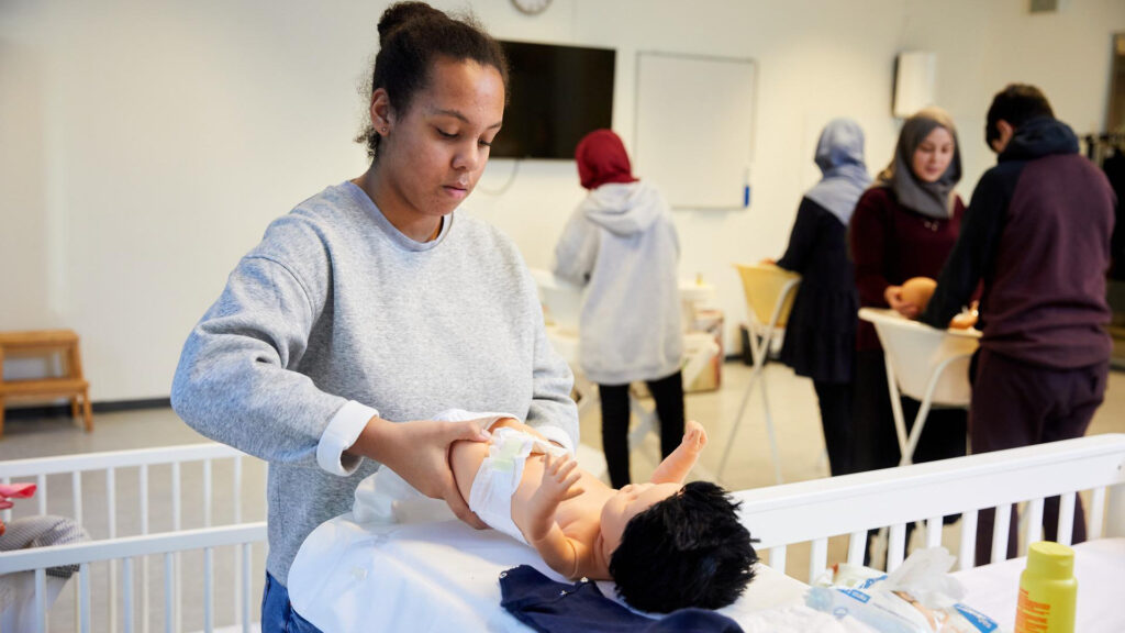 Een student oefent met het verschonen van een babypop