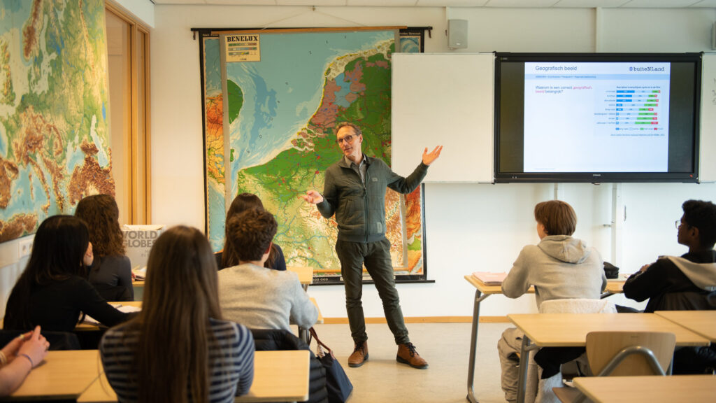 Een leraar aardrijkskunde staat voor de klas en geeft les